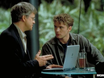 Two men talking over a laptop