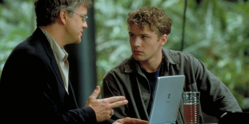 Two men talking over a laptop